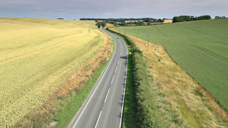 Drone-captures-the-peaceful-countryside-of-Lincolnshire,-with-farms,-fields,-and-a-winding-country-road