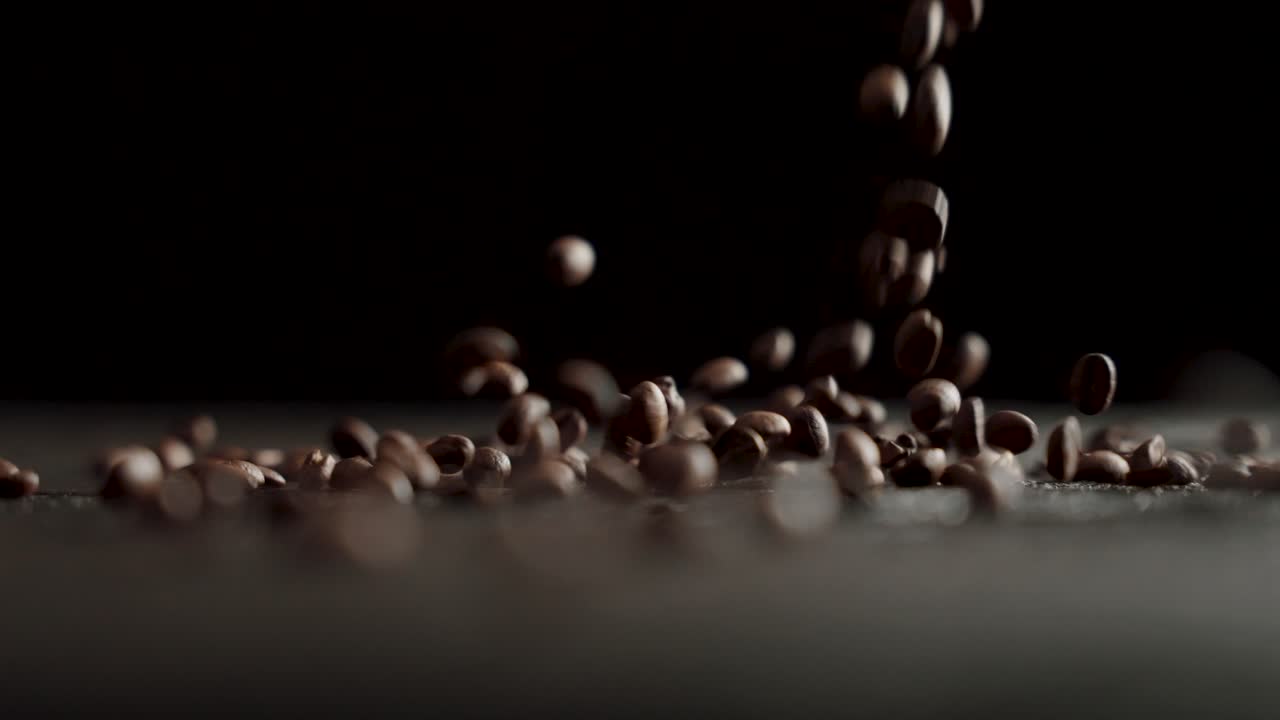 los granos de café caen en cámara lenta sobre una mesa con fondo negro - 120fps