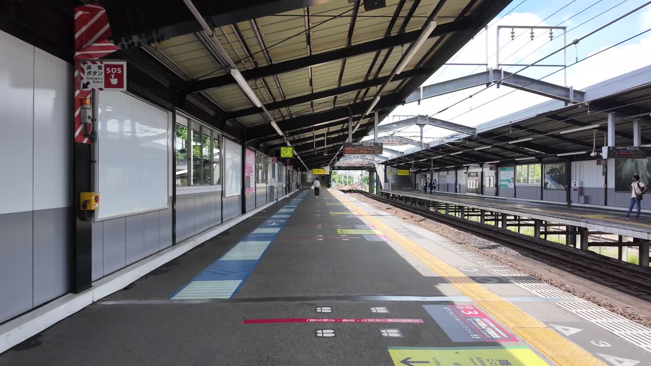 A view of an empty train station platform with tracks and overhead structures