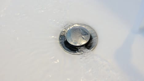 4k close up streaming water in sink. water stream going down the drain. water is running from open faucet into sink.