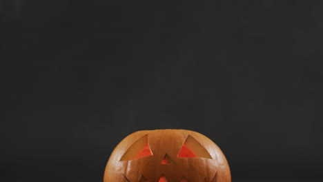 Raucheffekt-über-Gruseligem-Gesicht-Geschnitzter-Halloween-Kürbis-Vor-Grauem-Hintergrund