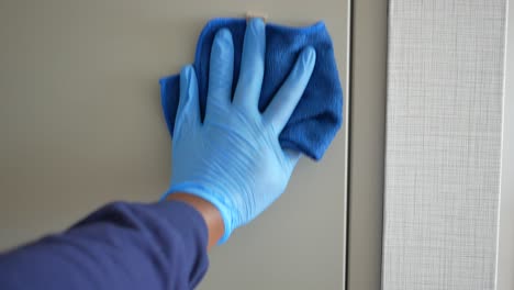 a person wearing blue gloves cleans a surface with a cleaning cloth