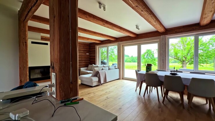 Ampio soggiorno e cucina moderni con grandi finestre che si affacciano su un paesaggio verde