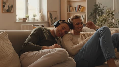 two men sharing headphones and relaxing on a couch