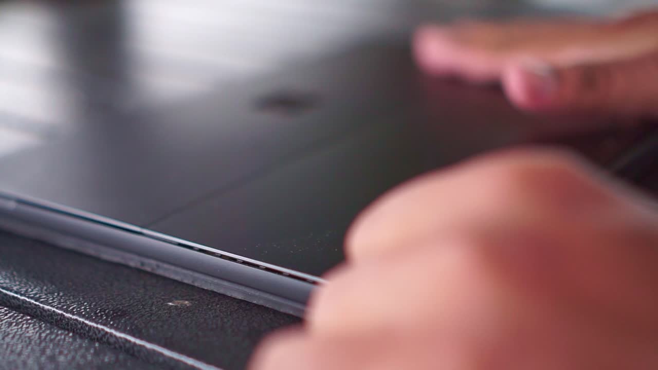 Persona che posiziona un tablet su una scrivania nera, dettaglio ravvicinato, dispositivo digitale, allestimento minimale dell'ufficio.