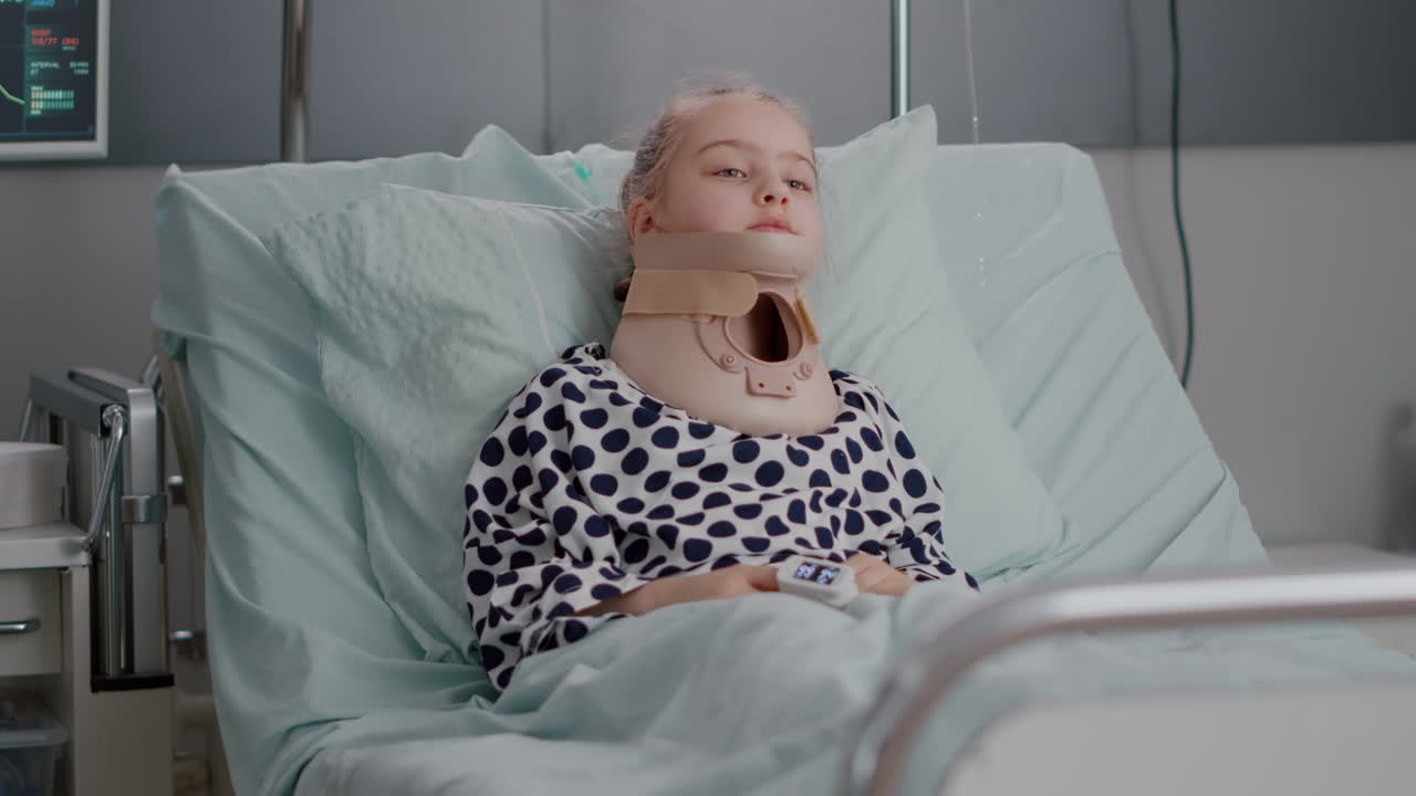 Portrait of sick child patient lying in bed looking at camera while having neck cervical collar