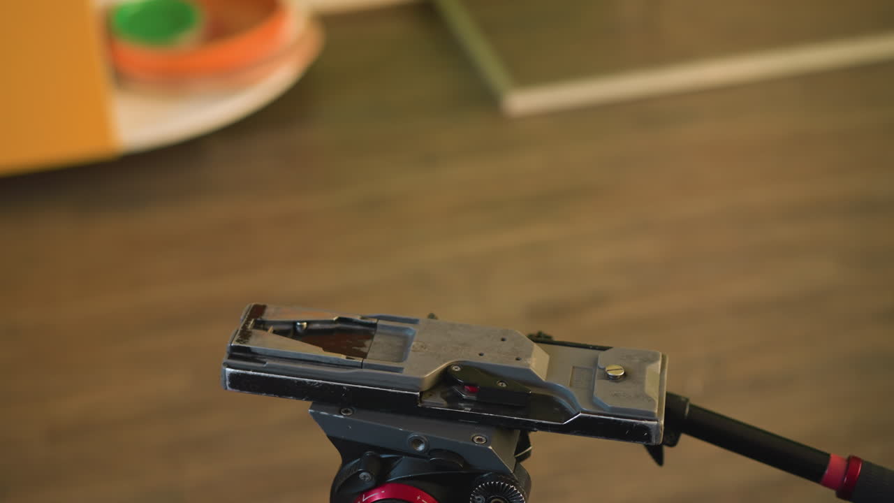 cameraman adjusting camera on tripod, attaching microphone for video production, hand holding camera controls, preparing for professional filming, shot setup in studio, camera ready for action