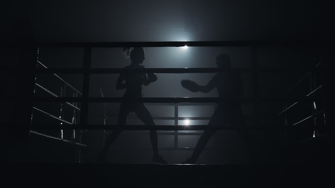 Silhouette di pugili che si allenano in un ring scarsamente illuminato