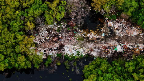 piles of rubbish in green and lush jungle forest, aerial top down view