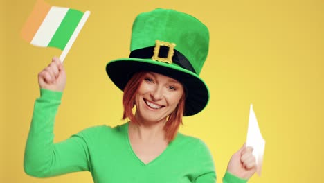 zabawna kobieta w kapeluszu leprechauna i tańczące irlandzkie flagi