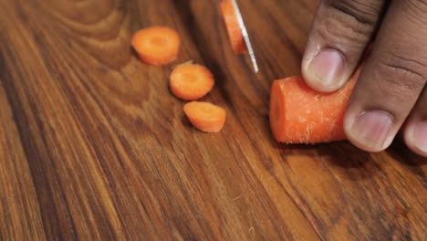 Primer-Plano-De-Las-Manos-Cortando-Zanahoria-En-Una-Tabla-De-Madera---Cortando-Verduras-En-Trozos-Pequeños-Con-Un-Cuchillo