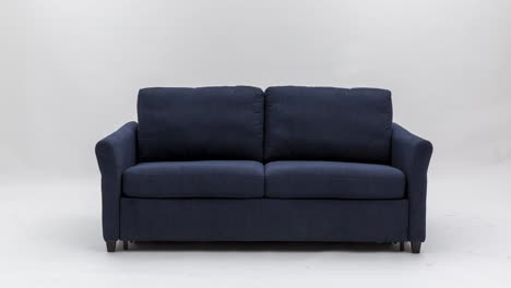 Die-Kamera-Zoomt-Langsam-Auf-Das-Ausziehbare-Sofa-Aus-Blauem-Stoff-Vor-Weißem-Hintergrund