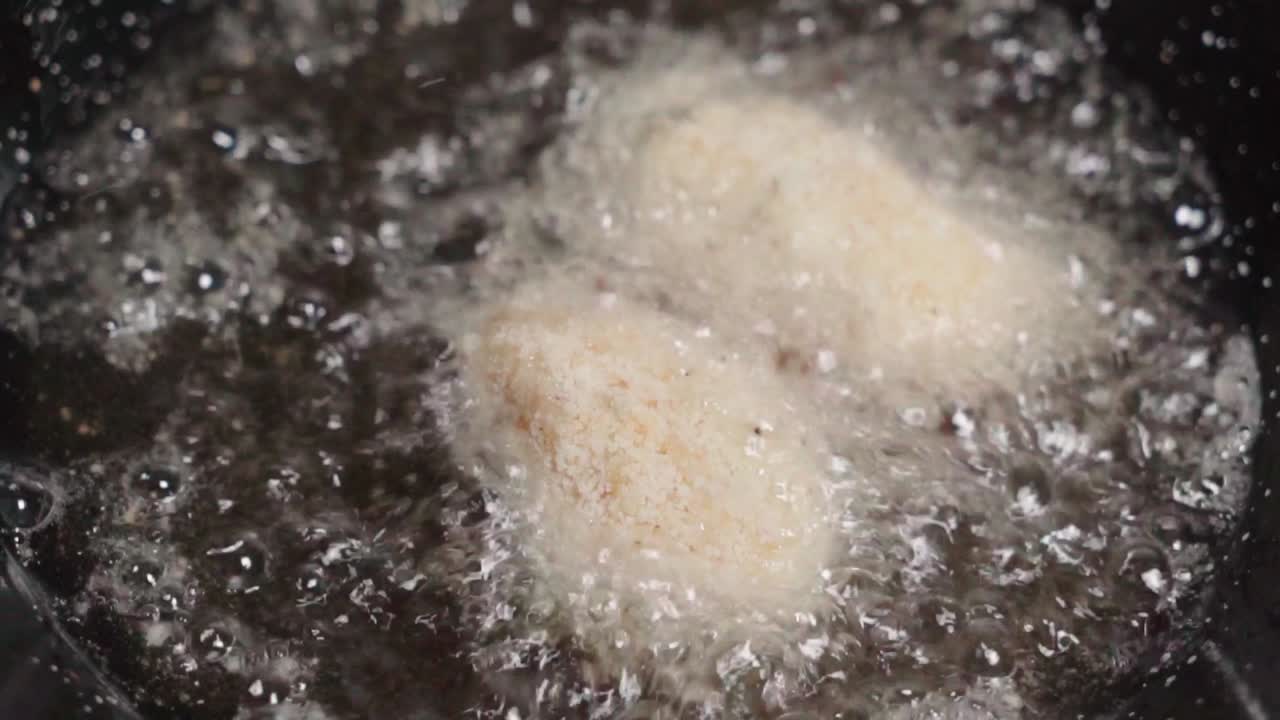 주걱을 사용하여 익히지 않은 크로케타를 뜨거운 올리브 오일에 넣고 닫습니다.