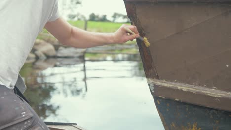 carpenter applying polyurethane wood hardener to wooden boat bow