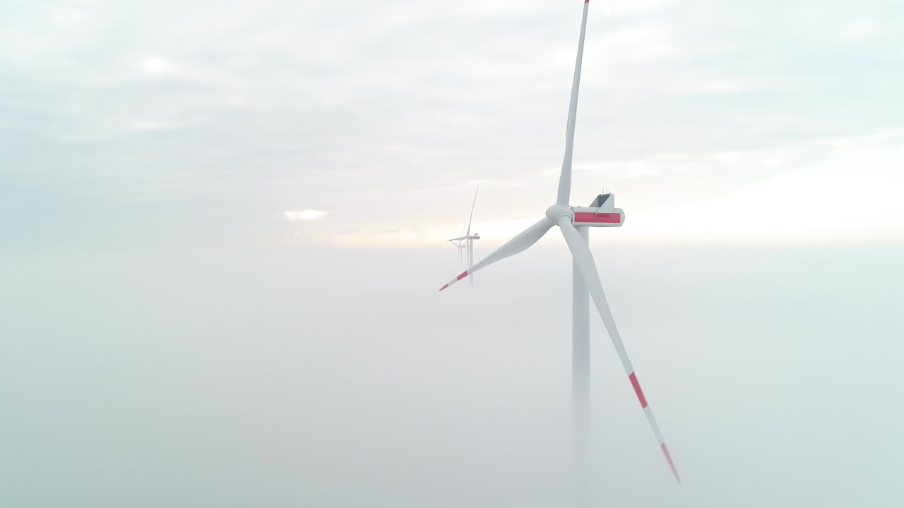 짙은 안개 층 위에 있는 풍차 터빈의 공중 샷으로 녹색 청정 에너지를 생산합니다.