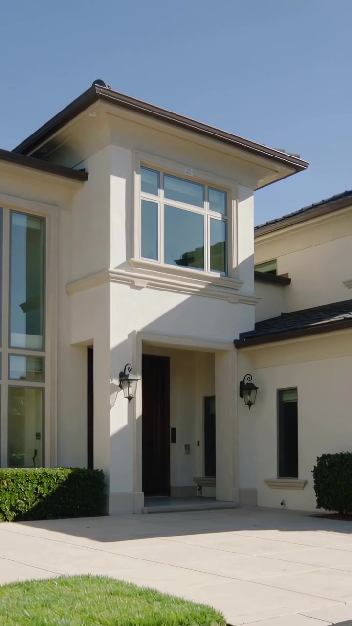 Vídeo vertical: Câmera iniciando panorâmica da entrada frontal de casa de dois andares, revelando lanternas da varanda
