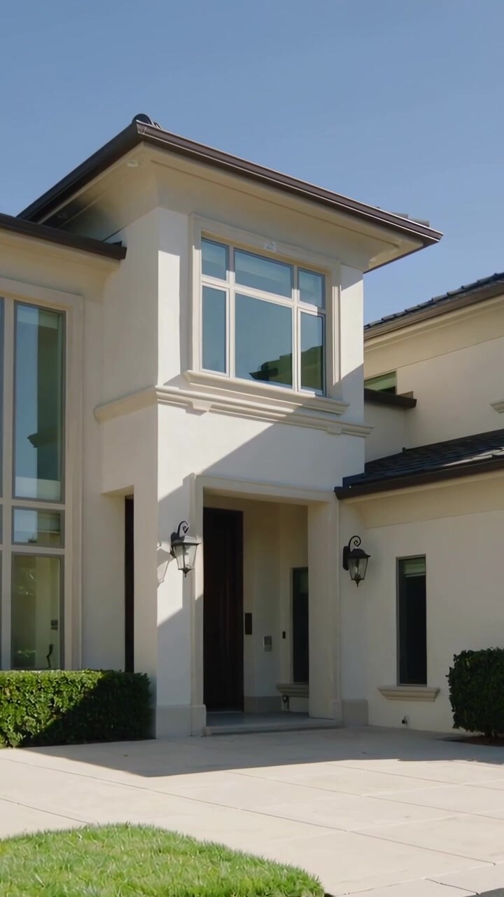 Video verticale: La telecamera inizia a panoramare l'ingresso principale di una casa a due piani, rivelando le lanterne del portico