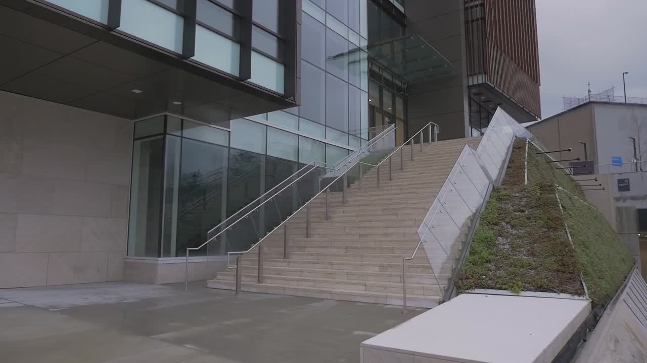 modern glass cement building in new urban city  development modern skyscraper residential living real estate brentwood burnaby BC canada panning right to reveal cement staircase steps lobby entrance
