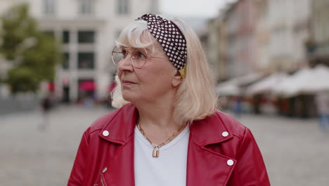 portrait of senior woman tourist walking in urban city street smiling having positive good mood