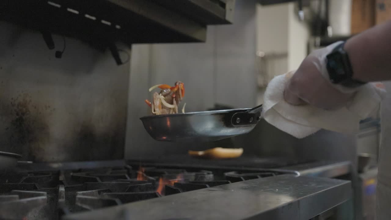 Chef che gira la salsiccia in padella