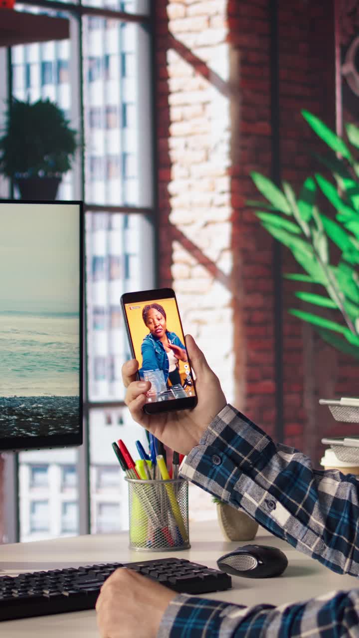 Vertical video Man in home office looking at social media feed with live broadcasts