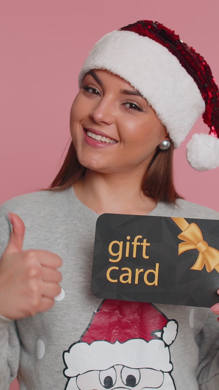 Woman showing pointing on gift discount certificate christmas voucher coupon for store holidays sale