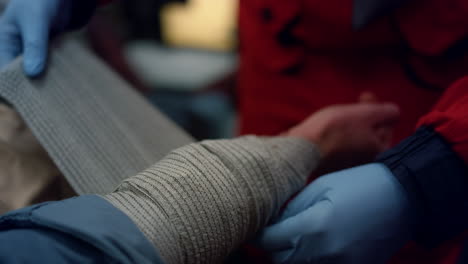 Female-medic-bandaging-arm-of-injured-man