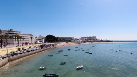 Slow-Motion-view-over-boats-at-beach-with-low-tide-ocean-and-blue-sky