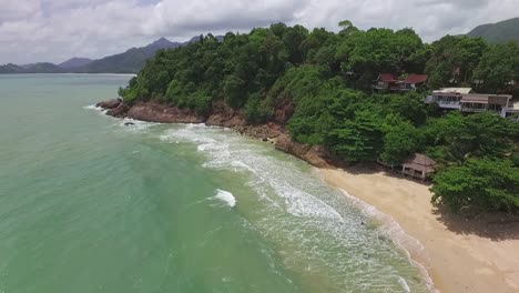 Dolly-Aerial-shot-of-tourist-beach-in-tropical-Koh-Chang-with-small-resorts-and-Jungle-sea-view