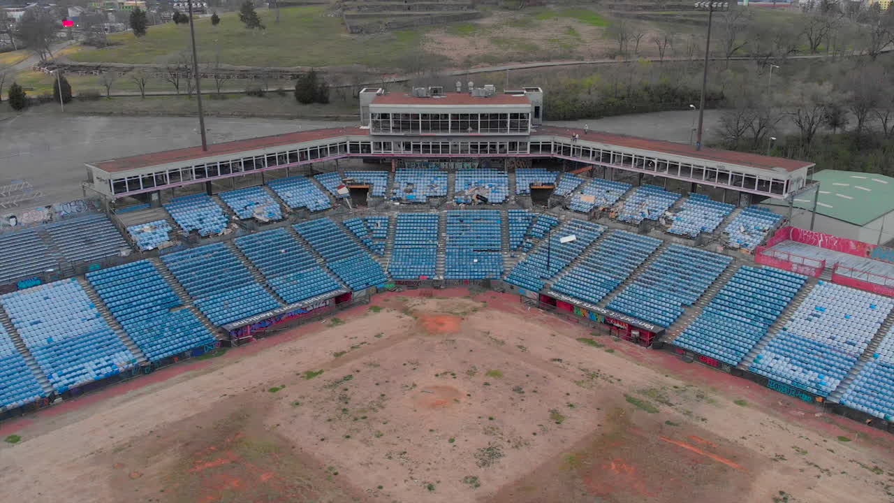 멀리 떨어진 십대들이 버려진 야구장 꼭대기에서 놀고 있다.