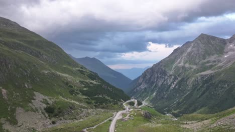 drone pushes towards stunning natural beauty of furkapass, switzerland, calm mountains and pathway under cloudy weather