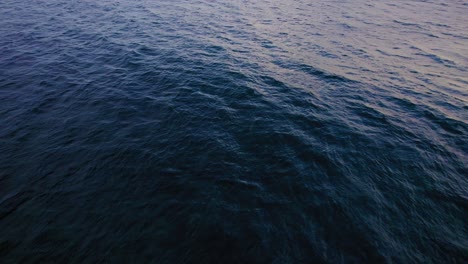 Aerial-tilt-up-shot-from-ocean-waves-into-the-sunset