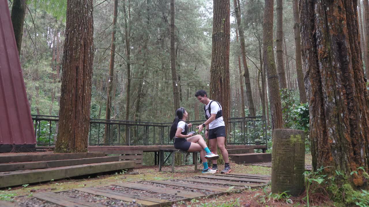 Asian couple taking photo with smartphone during outdoor trail run in Indonesian forest