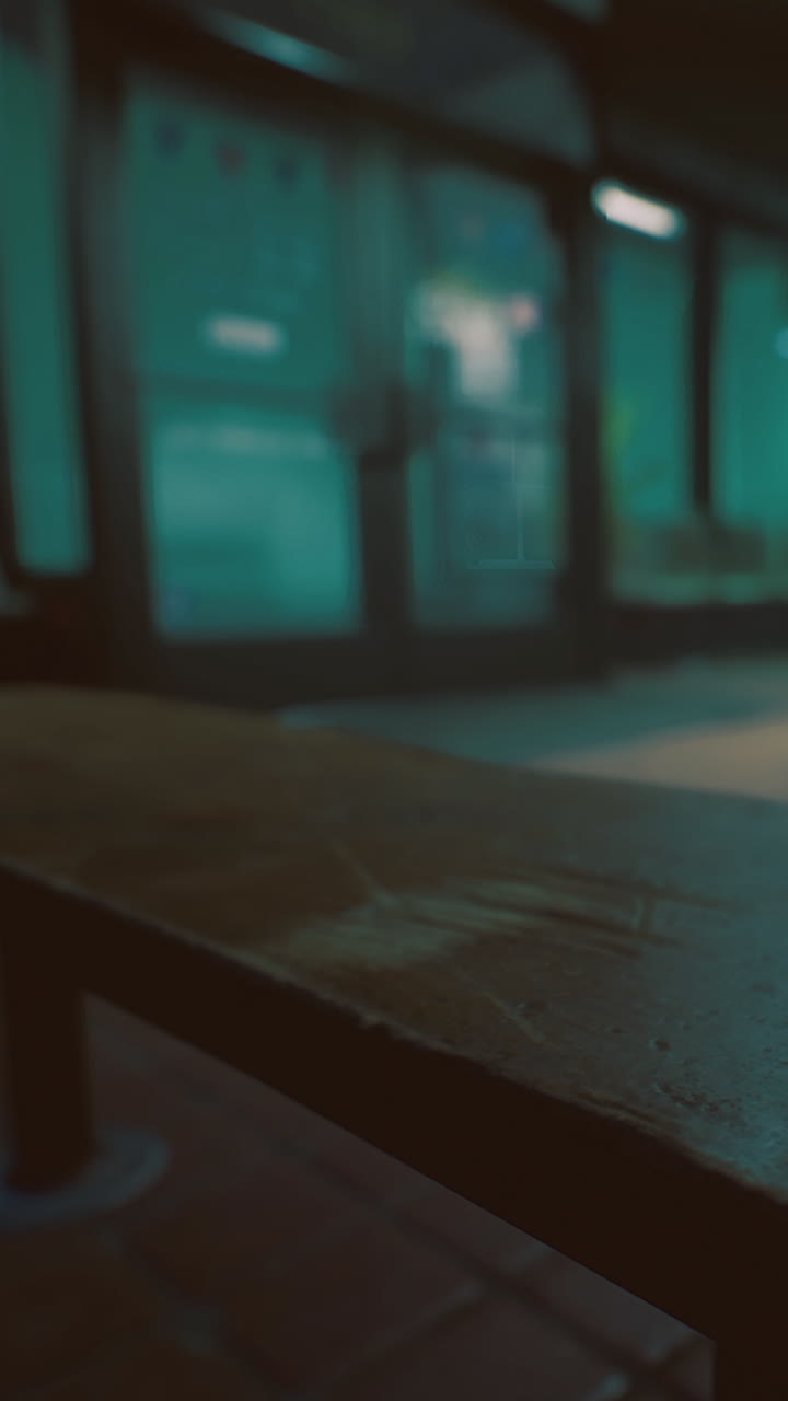 Scena urbana con panca di legno e vetrina sfocata di sera.