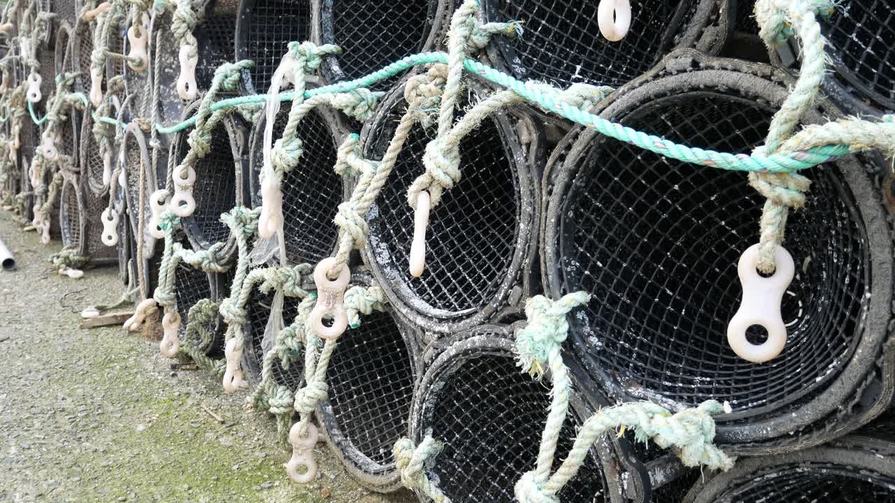 Close up Fishing harbour group of stacked lobster pots on coastal marine waterfront pull back