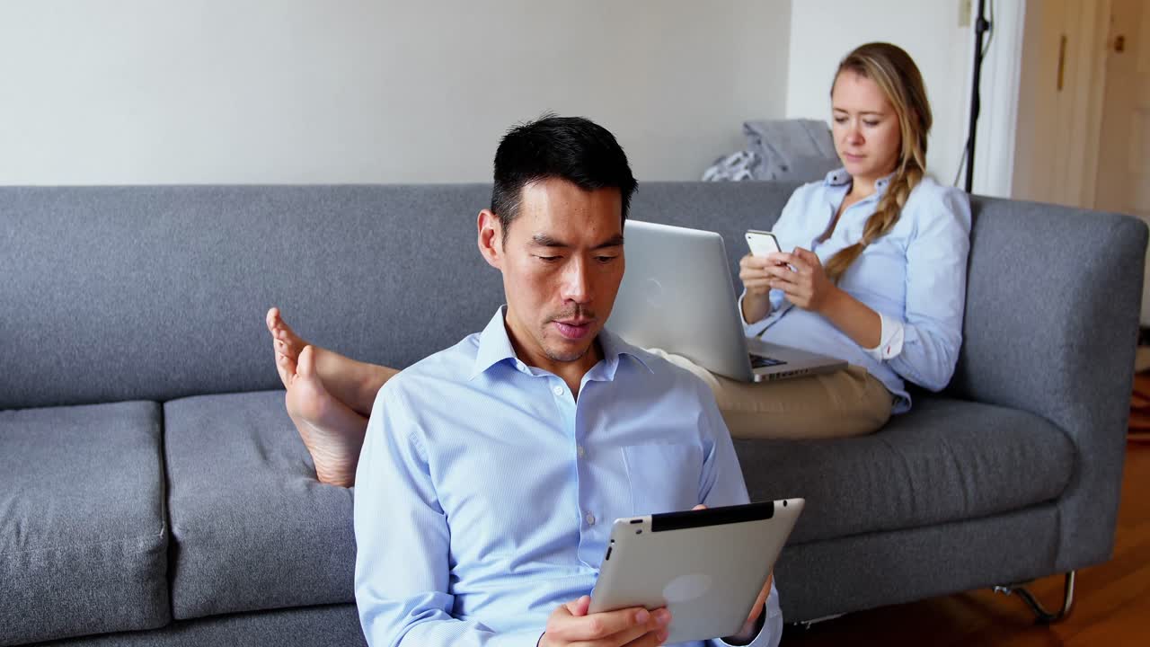 여성이 휴대폰을 사용하는 동안 디지털 태블릿을 사용하는 남자