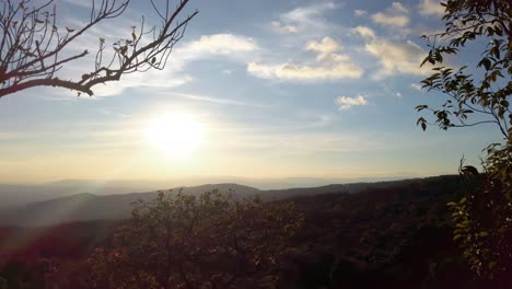 the beautiful sunrise in the mountains of thailand surrounded with lush trees and grass - wide shot