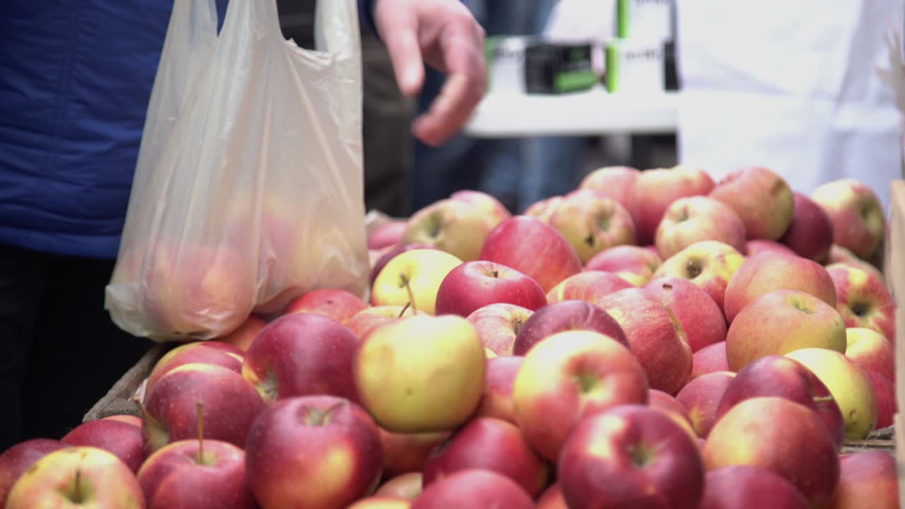 Costumer choosing red apples in city fruit and vegetable market. Buyer picking red juicy apples in farmers market