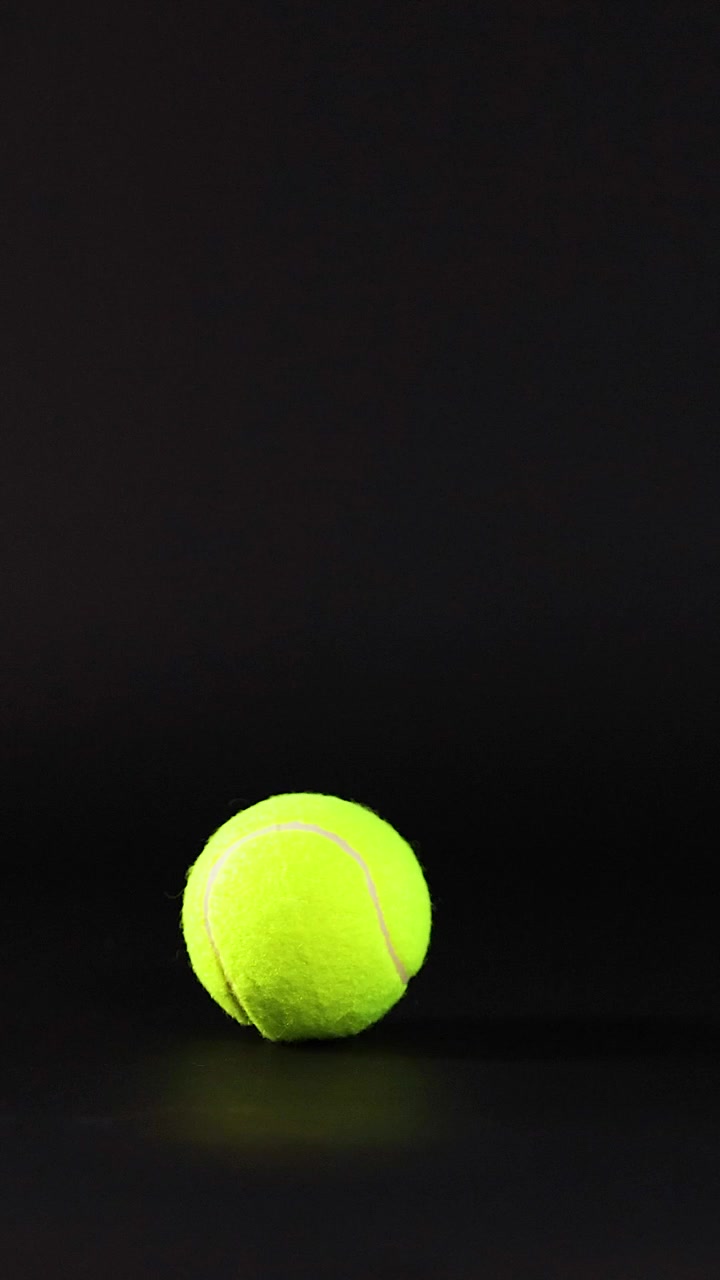 Tennis ball rolling across a dark background