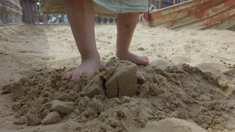 shot of a child's legs stomping on a small sand castle