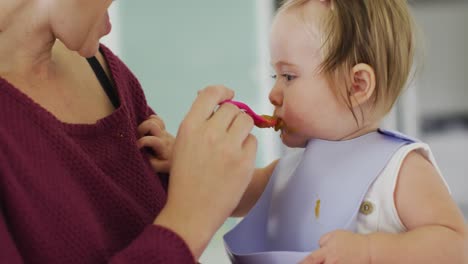 close up of caucasian mother feeding her baby at home