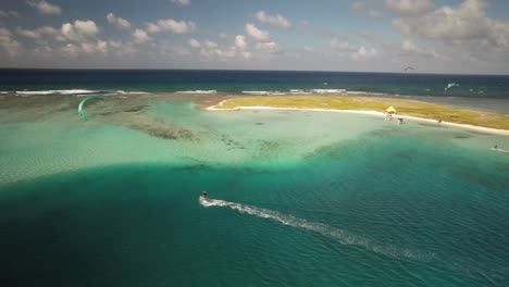 Kitesurfer-gliding-over-crystal-clear-turquoise-waters-near-a-small-island