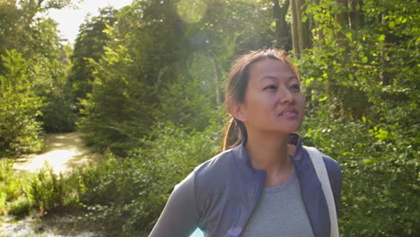 운동복을 입고 요가 매트를 들고 있는 여성이 숲 속의 다리 위에 서서 자연의 평화와 아름다움을 즐기고 있다.