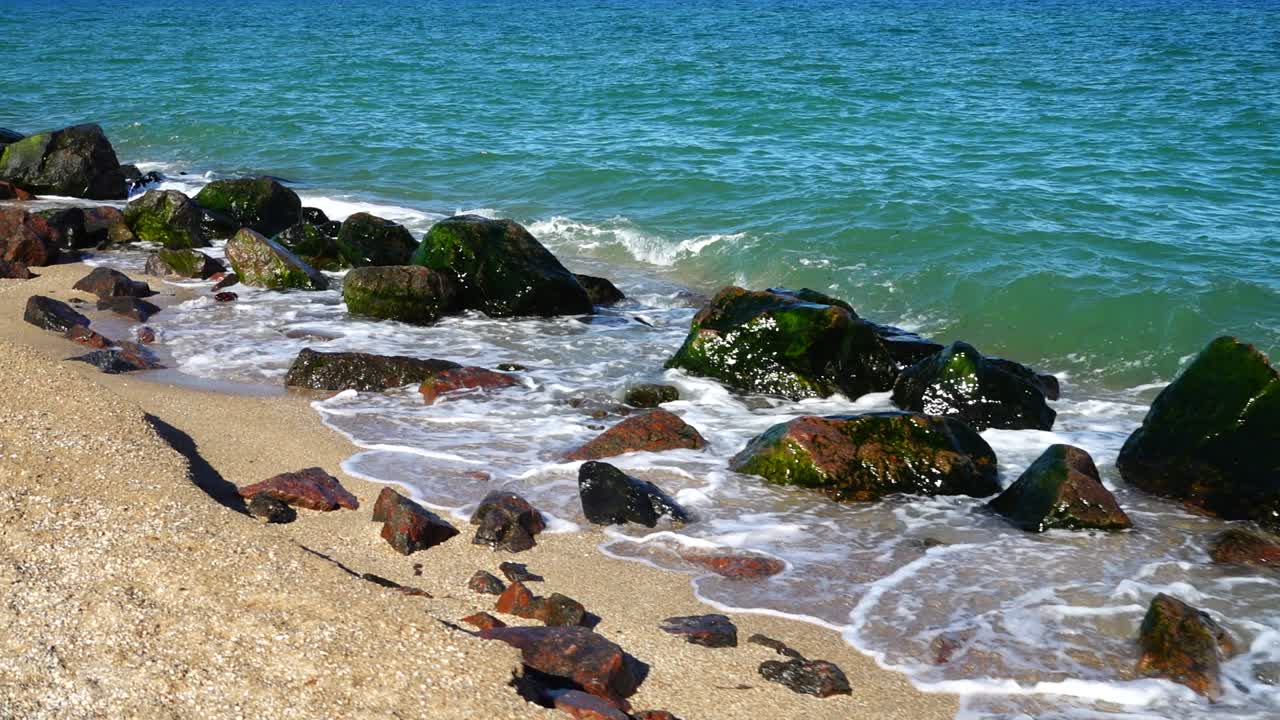 Sea waves break against stones. Shooting on the seashore. Slow motion