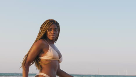 african swimwear model with braids having fun posing at the beach during a sunset