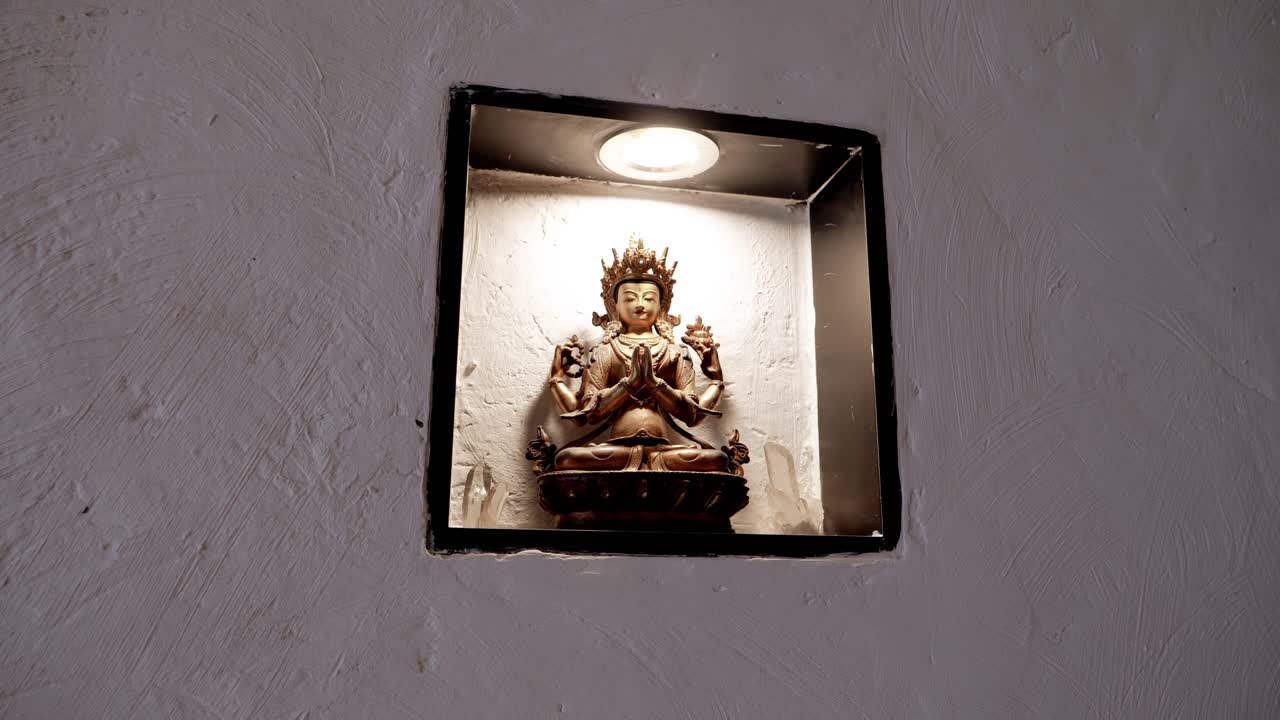 estatua de buda iluminada por un reflector en un nicho de pared empotrado