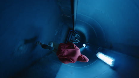 man running in dark underground tunnel with blue light