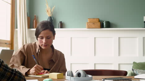 camera focuses on a girl of a study group writting sitting at table