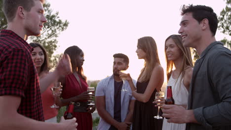 adult friends socialising at a party on a rooftop at sunset, shot on r3d