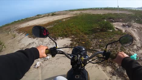 riding motorcycle on polluted coastal part of my hoa beach on sunny day. vietnam. driver pov
